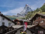 Tradycyjna winieta szwajcaria: drewniane domy z kamiennymi dachami i majestatyczny Matterhorn w tle.