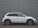 Biały Kia Niro EV widziany z boku na tle szarej, falistej ściany.