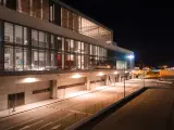 Nowoczesny budynek lotniska w nocy, z oświetlonymi oknami i pustymi drogami. Wygląda jak marbella lotnisko.