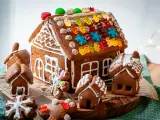 Kreative Ideen für ein Lebkuchenhaus: Ein detailreiches Lebkuchenhaus mit bunten Gummibärchen und kleinen Lebkuchenhäusern drumherum.