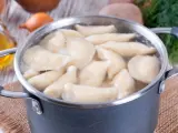 Pierogi gotują się w garnku. Woda wrze, a pierożki wypływają na powierzchnię. Czas gotowania pierogów jest kluczowy dla ich smaku.