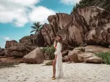 Kobieta w białej narzutce na plaży z granitowymi skałami w tle. Seszele atrakcje to raj dla miłośników przyrody i pięknych krajobrazów.