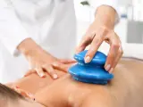 Masaż bańką chińską: terapeuta wykonuje zabieg na plecach pacjenta. Choć zazwyczaj przynosi ulgę, warto znać potencjalne masaż bańką chińską efekty uboczne.