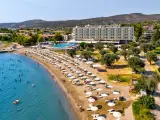 Piękna plaża na Evii, idealna na wycieczki fakultatywne. Hotel, basen, leżaki i mnóstwo ludzi kąpiących się w morzu.