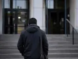 Mężczyzna w ciemnej kurtce wchodzi po schodach. W ręku trzyma torbę, jakby niósł ważny, żelazny list.
