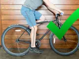 A cyclist demonstrates proper bike seat height with a slight knee bend at the bottom of the pedal stroke. A green checkmark confirms the correct adjustment.