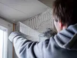 Hand mit Handschuh legt Armierungsgewebe an, um die Fensterlaibung zu verputzen.
