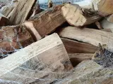 Gros plan sur un poids stère de bois sec, emballé dans un filet blanc, prêt pour l'hiver.