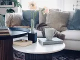 Ett stilrent soffbord med ribbad bas, perfekt för ditt hem. Här finns en bok, en mugg och en vas med blommor.