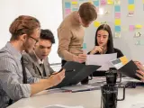 Studenci analizują wykresy, przygotowując się do zajęć z handlu międzynarodowego. Na tablicy notatki i pomysły.