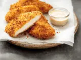 Délicieux poulet pané croustillant, coupé en deux pour montrer sa tendreté, servi avec une sauce crémeuse.
