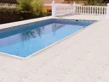 Piscina con borde de mosaico y suelos para piscinas que no quemen, de color claro y textura agradable.