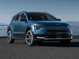 Niebieski Kia Niro Hybrid z nowoczesnym designem, zaparkowany na tle mglistego krajobrazu.