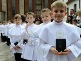 Chłopcy w białych albach, gotowi do komunii, trzymają modlitewniki. Jeden z nich uśmiecha się do aparatu.