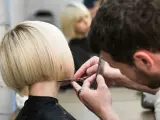 Fryzjerka tworzy modne fryzury odmładzające po 40 krótkie. Blond bob jest precyzyjnie cięty.