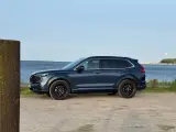 Nowa Honda CRV w ciemnoniebieskim kolorze zaparkowana przy wodzie.