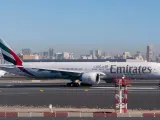 Samolot Emirates na płycie lotniska, w tle panorama Dubaju. Zastanawiasz się, ile się leci do Dubaju?