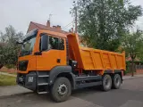 Pomarańczowy wywrotka c1 stoi na ulicy, gotowa do pracy.