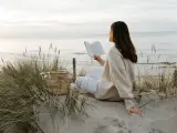 Kobieta czyta książkę na plaży, ciesząc się spokojem i świeżym powietrzem. To idealny moment, by poczuć, kiedy jest najwięcej jodu nad morzem.