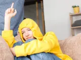 Ein Teenager in gelbem Hoodie zeigt seiner Mutter den Mittelfinger. Er hat keinen Respekt vor ihr.