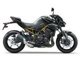 Stylowy, czarny Kawasaki Z900 z widoczną złotą ramą, gotowy na podbój dróg.