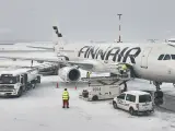 Samolot Finnair na lotnisku w śnieżny dzień. Pracownicy obsługi naziemnej przygotowują samolot do lotu. Czy do Finlandii można lecieć na dowód?