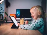 Uśmiechnięta dziewczynka ogląda ulubionych youtuberów dla dzieci na tablecie.