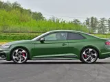 Zielony sportowy coupe z czerwonymi zaciskami hamulcowymi jedzie po torze.