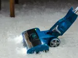 Blauer Staubsauger mit LED-Licht reinigt flauschigen Teppich. Die Leistung, wie viel Watt hat ein Staubsauger, ist entscheidend für die Saugkraft.