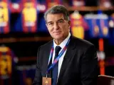 Uśmiechnięty prezes Barcelony, Joan Laporta, w garniturze, z identyfikatorem FC Barcelona na szyi.