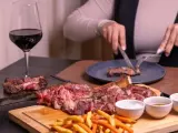 Idealne **jakie wino do wieprzowiny**? Czerwone wino i soczysta wieprzowina na desce, z frytkami i sosami.