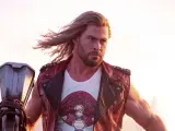 Thor, z rozwianymi blond włosami i brodą, w skórzanej kamizelce i koszulce z symbolem młota, trzyma swój potężny oręż.
