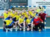 Drużyna Unii Tarnów piłka ręczna świętuje zwycięstwo. Radośni zawodnicy w żółto-niebieskich strojach pozują do wspólnego zdjęcia.