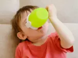 Małe dziecko pije z zielonego kubka niekapka LOVI.