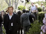 Simon Baker, con la sua nuova fidanzata, è circondato da telecamere e microfoni durante un evento all'aperto.