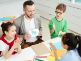 Nauczyciel pokazuje literę "Pp" podczas zebrania z rodzicami. Dzieci klaszczą, ucząc się alfabetu.