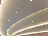 Nowoczesny podwieszany sufit z ukrytym oświetleniem LED tworzy łagodne, faliste linie, dodając przestrzeni elegancji.