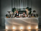 Dwóch barmanów przygotowuje drinki przy nowoczesnym, podświetlanym barze. To idealny drink bar na wesele, oferujący orzeźwiające napoje.