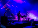 Un groupe allemand des années 2010 joue sur scène sous des lumières bleues et violettes.