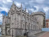 Kamienne mury i strzeliste wieże zdobią zamek w Dublinie. Gotycka architektura i chmurne niebo tworzą majestatyczny widok.