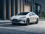 Biały sedan BYD Seal 6 DM-i jedzie po miejskiej ulicy.
