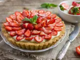 Tarta z truskawkami i kremem, ozdobiona listkami mięty.