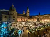 A magical Salzburg Austria Christmas market glows at night, with stalls, trees, and the cathedral creating a festive scene.