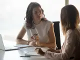 Kobiety omawiają umowę na zastępstwo. Jedna z nich wskazuje na dokument, druga słucha uważnie.