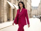 Elegancka kobieta w garniturze w intensywnym fuksja kolorze idzie ulicą.