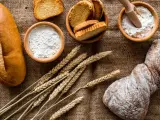 Brot, Getreideähren und Schalen mit Mehl, darunter Vollkornmehl aus Deutschland, liegen auf Jute.