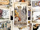 Karta Tarota "The Empress" w otoczeniu innych kart. Królowa siedzi na tronie, trzymając berło, symbolizując płodność i obfitość.