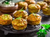 Deliziosi tortini di zucchine dorati, guarniti con rosmarino, su un piatto di ghisa. Sullo sfondo, una ciotola di formaggio fresco.