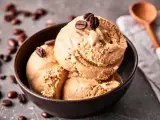 Kaffee Eis in einer Schale, garniert mit Kaffeebohnen. Ein Löffel liegt daneben.