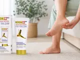Kobieta masuje stopę, łagodząc ból związany z ostrogami piętowymi. Obok balsam Krok Med Foot Balsam.